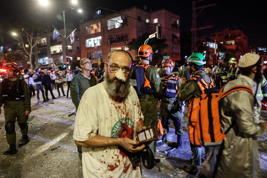 Civil ferido caminha entre socorristas, em Ramat Gan, ao lado de Tel Aviv