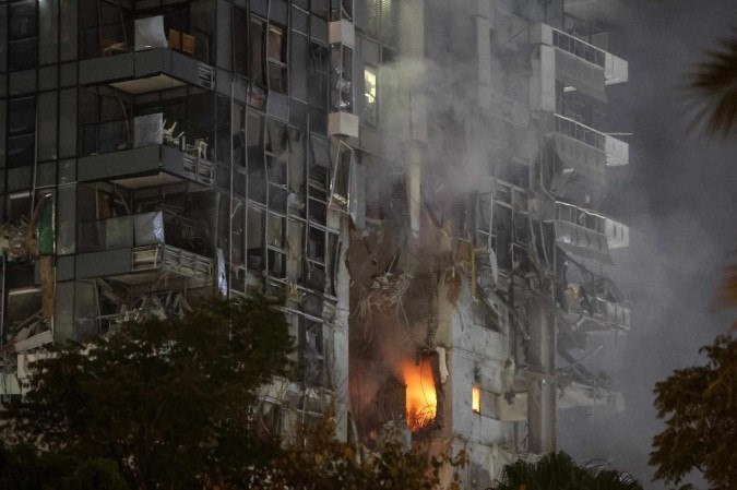 Fogo e fumaça sobem de edifício impactado por míssil, no centro de Tel Aviv - (crédito: Jack Guez/AFP)